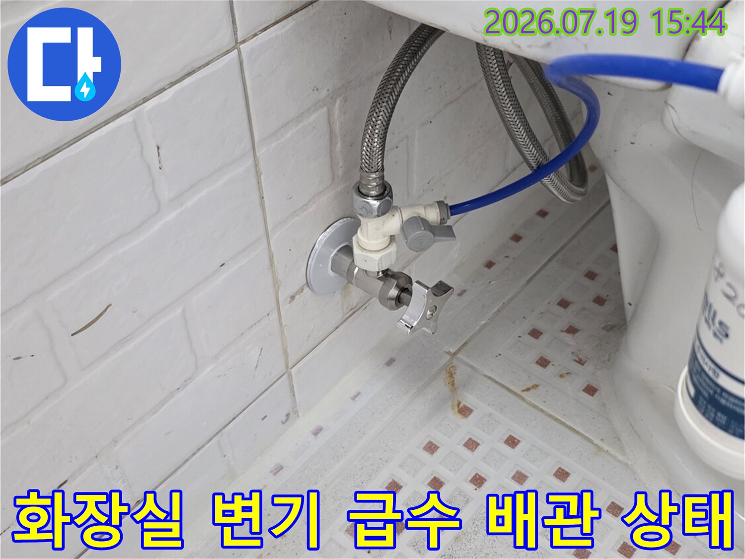화장실 벽면에 설치된 변기 급수 밸브와 연결된 파란색 호스-금속제 유연한 배관 모습