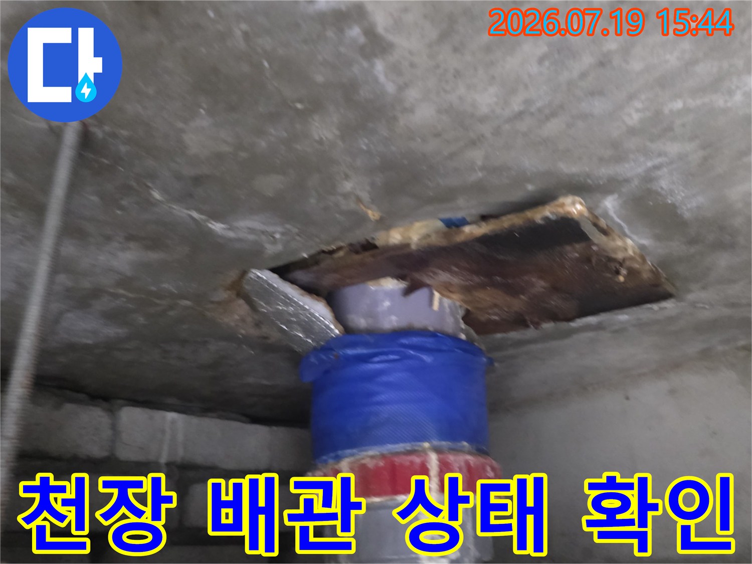 화장실 천장 슬래브의 구멍을 통해 파란색 보온재가 감싸진 배관이 노출된 모습