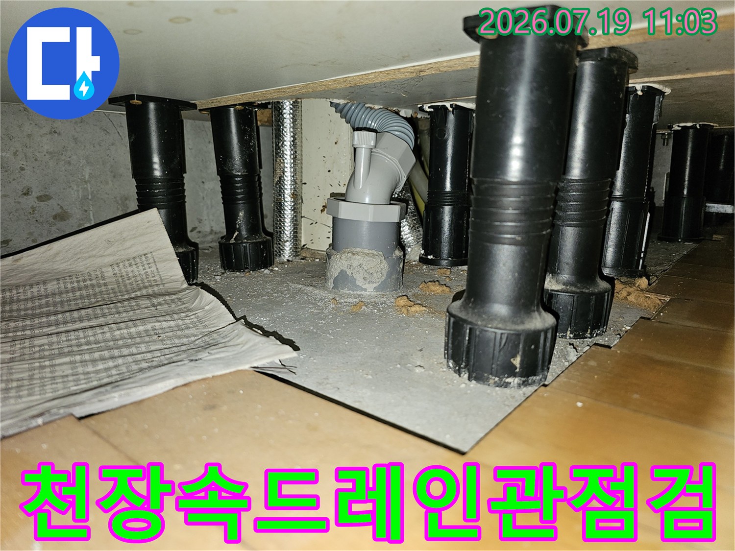 천장-바닥면에-고정된-회색-드레인-배관과-검은색-지지대들의-모습