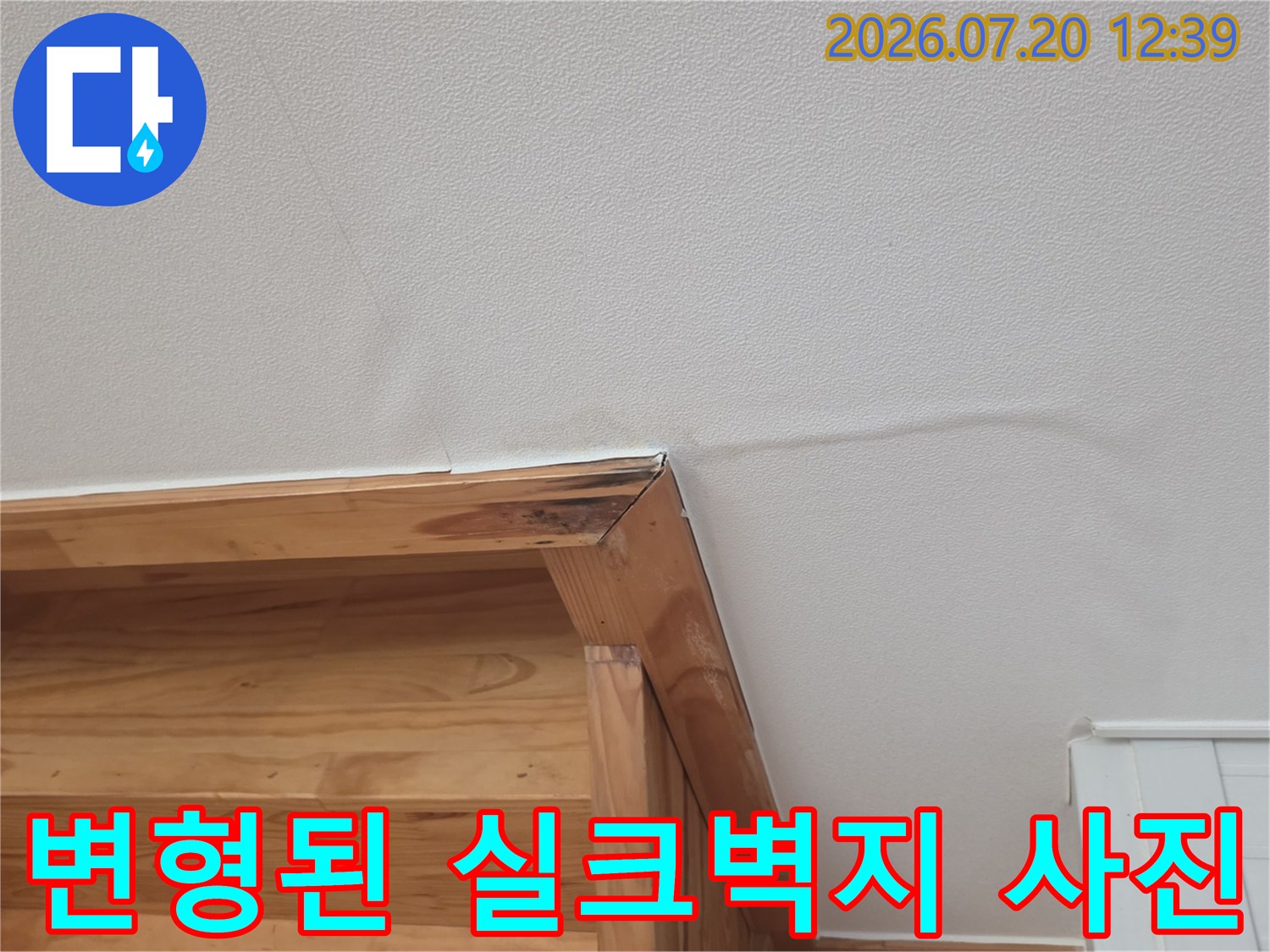 나무 선반 상단의 흰색 벽지가 습기로 인해 울퉁불퉁하게 부푼 모습