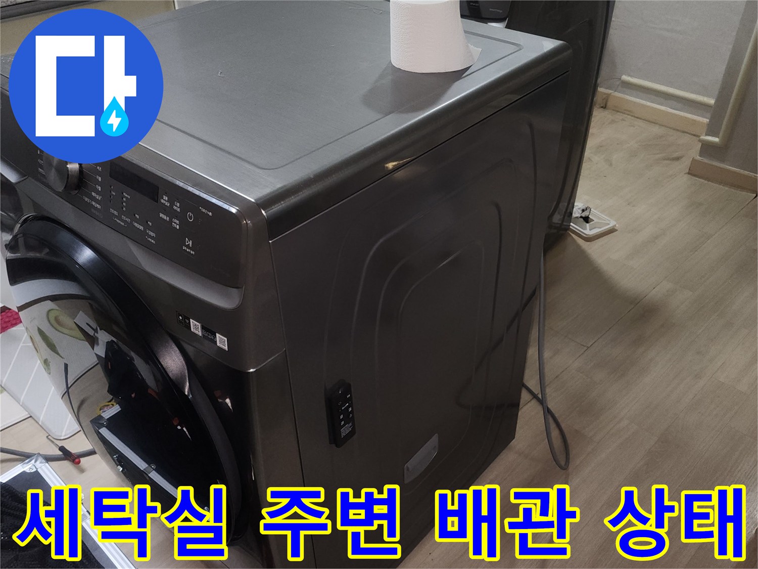 세탁기와 건조기가 설치된 세탁실 바닥 및 벽면 배관 근처 모습입니다.