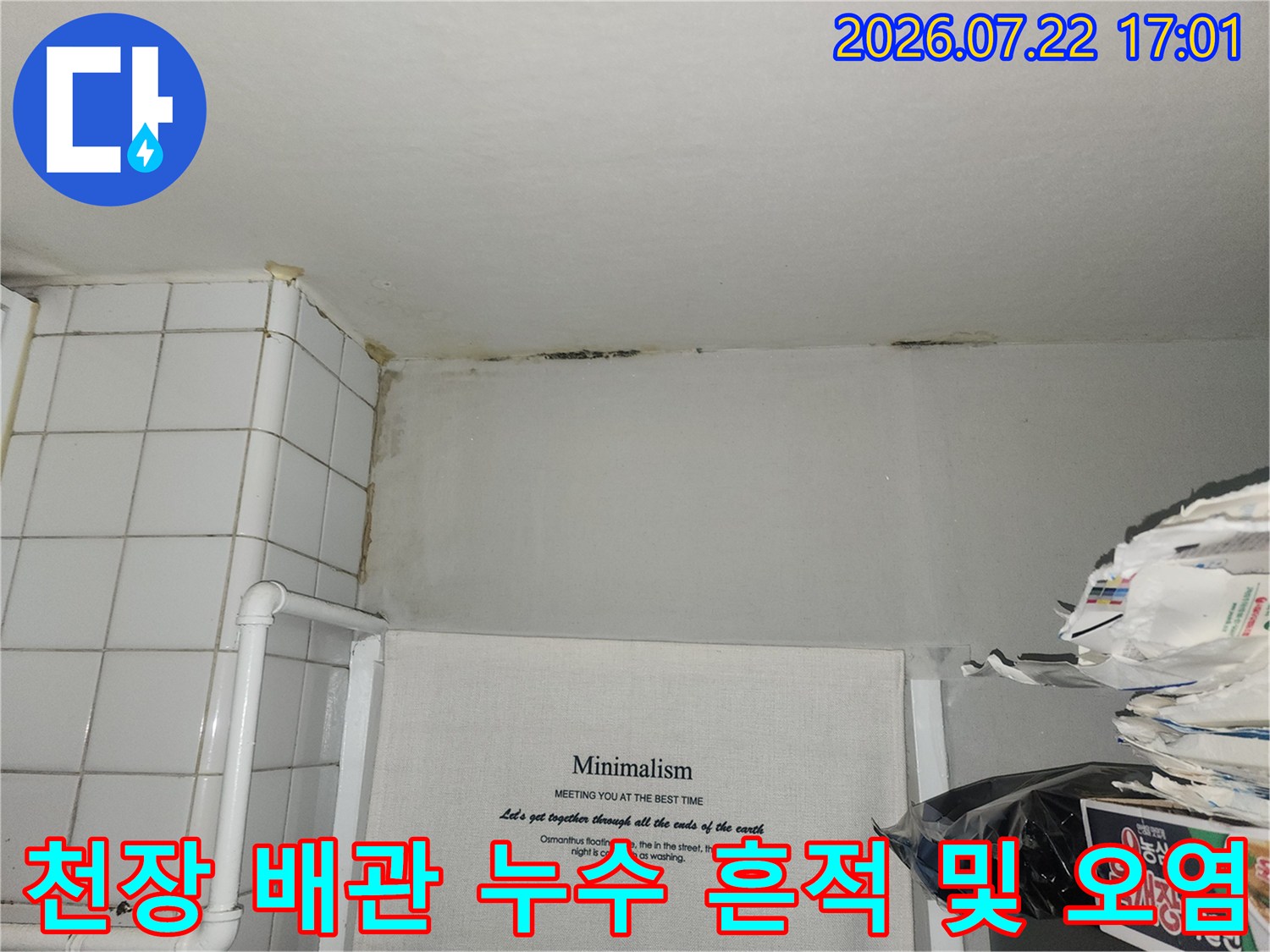 화장실 천장 끝부분의 습기 얼룩과 노출된 수도 배관