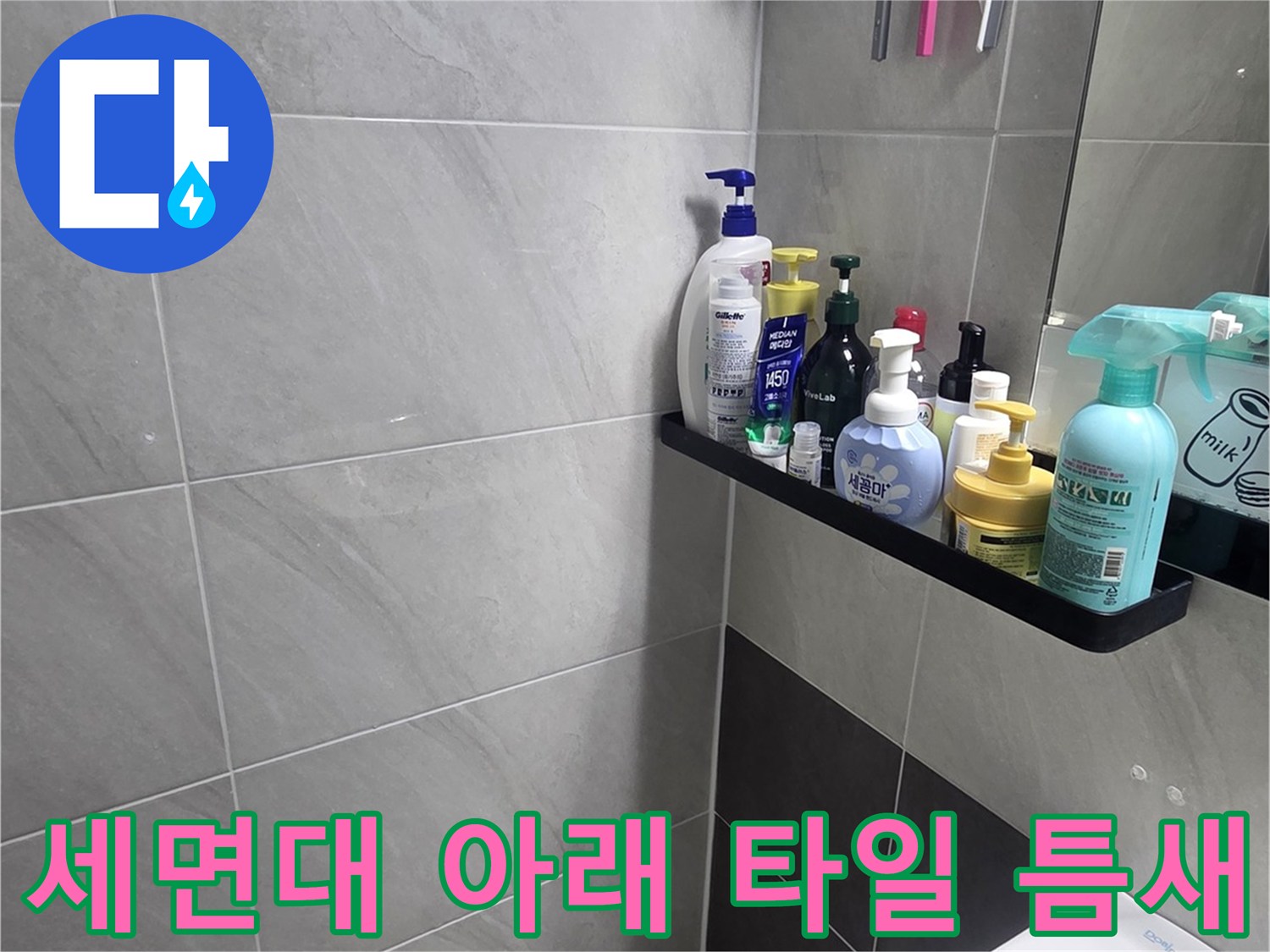세면대 하단 타일 사이의 미세한 균열과 오염된 줄눈을 나타냅니다.