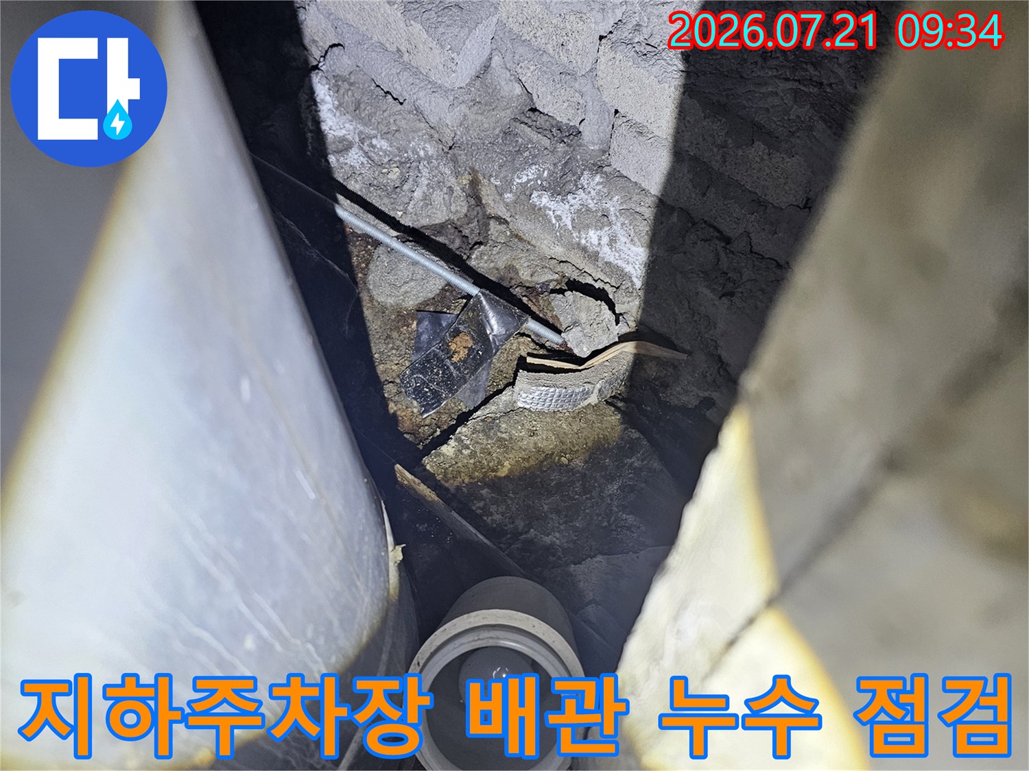지하 주차장 천장의 노출된 배관과 균열된 슬래브 부분의 누수 점검 현장