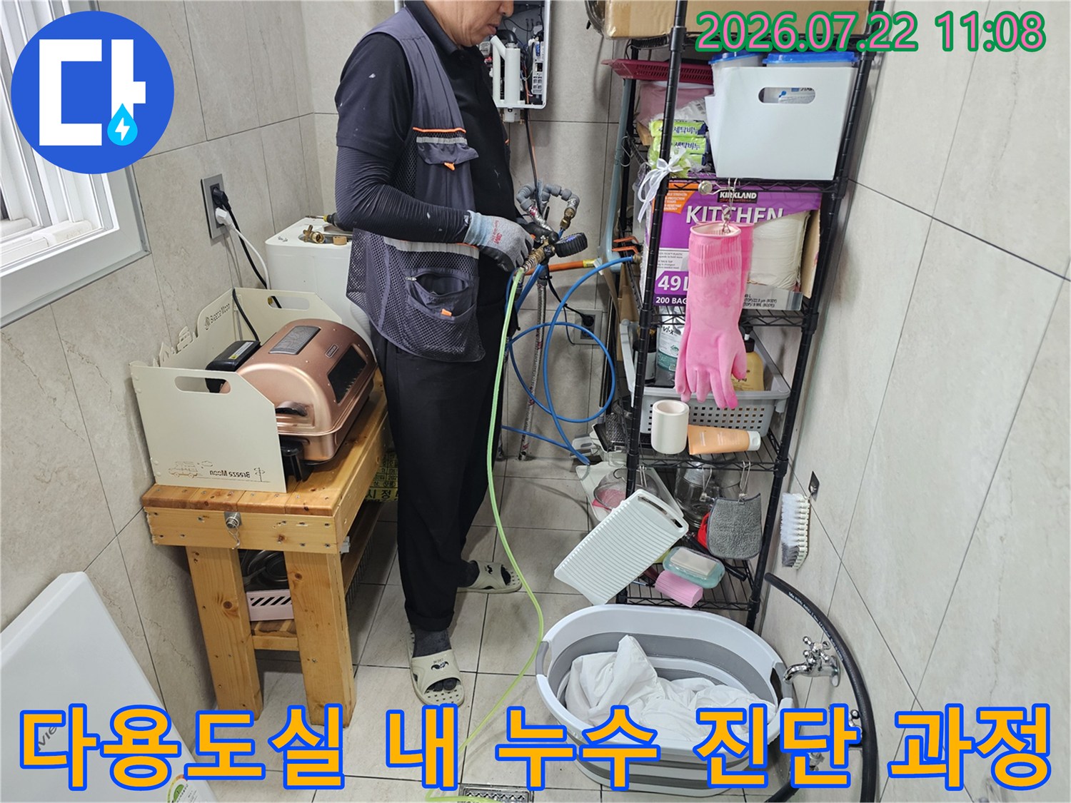 작업자가 장비를 이용해 다용도실 배관의 압력을 측정하고 있는 사진