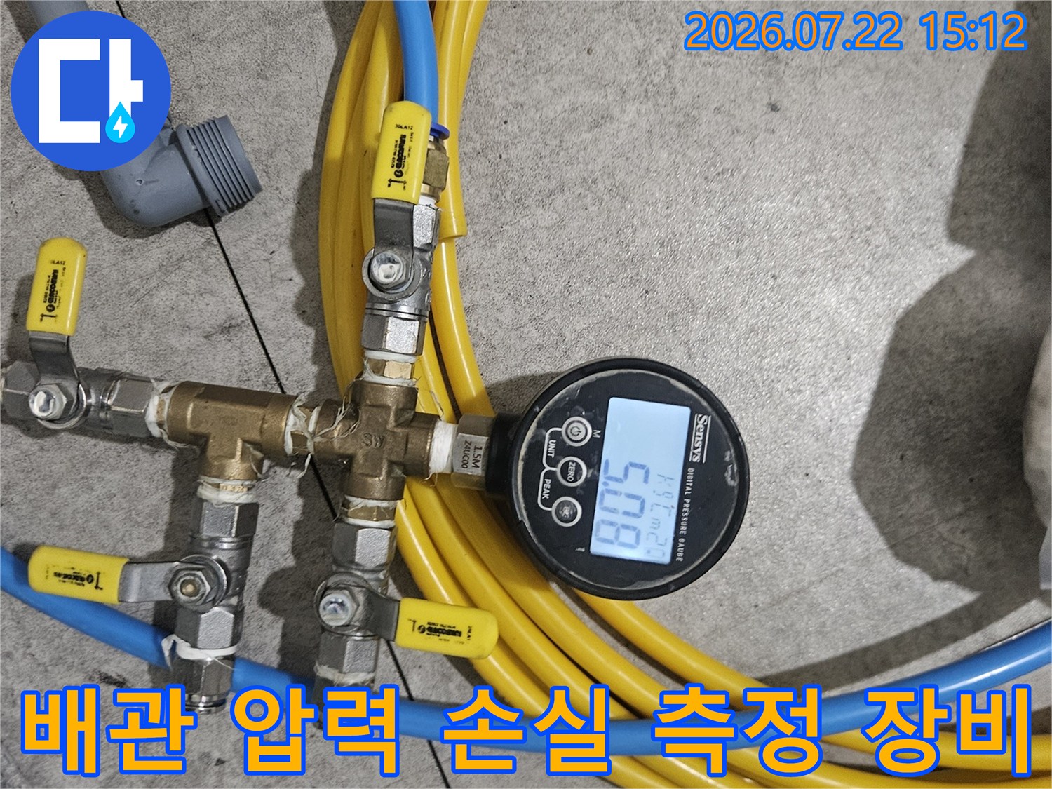 노란색 호스가 똬리를 틀고 있고 중앙에 디지털 압력계가 배치된 모습