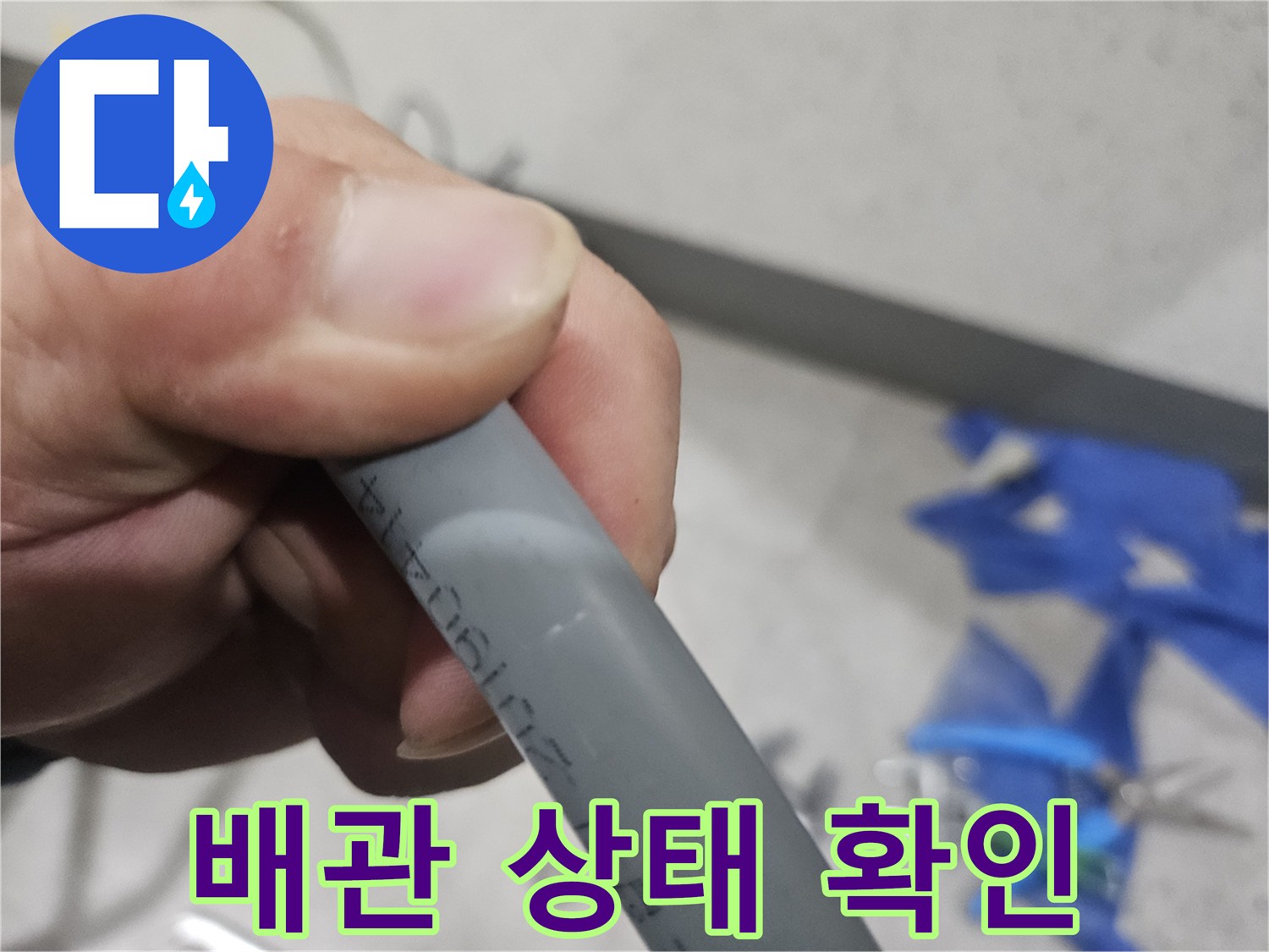 누수 점검을 위해 손으로 직접 잡고 확인 중인 회색 배관