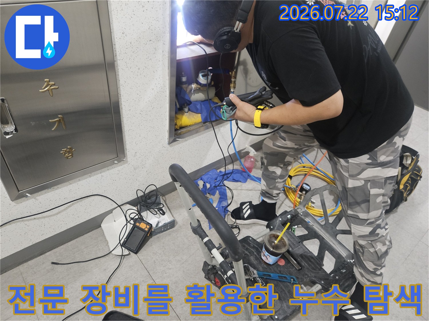 작업자가 배관 점검함 앞에서 가스 탐지기를 들고 누수 여부를 정밀하게 측정하는 모습