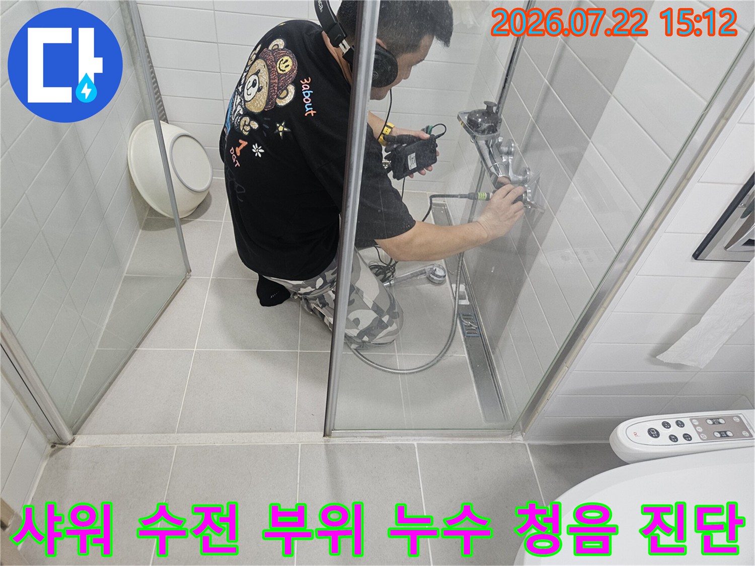 화장실 내에서 엔지니어가 헤드셋을 쓰고 수전 배관 쪽의 누수음을 측정하는 전문적인 모습
