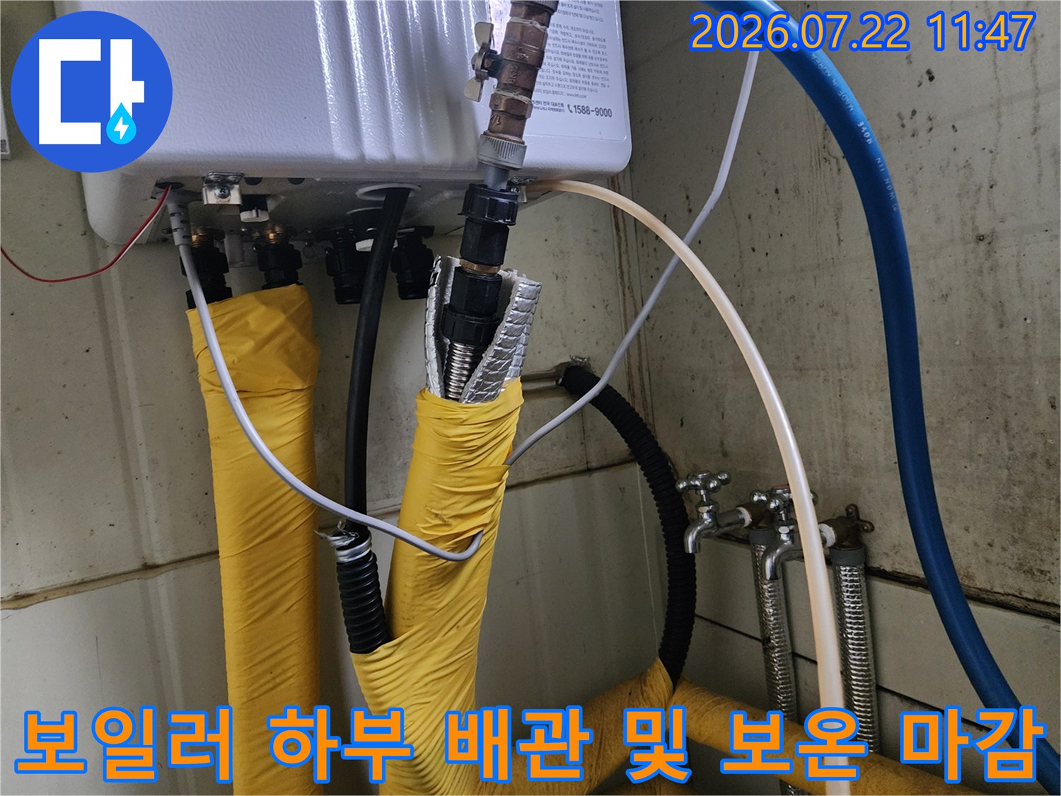 노란색 단열재로 감싸진 배관과 상단의 금속 밸브-보일러 하단 전경 사진