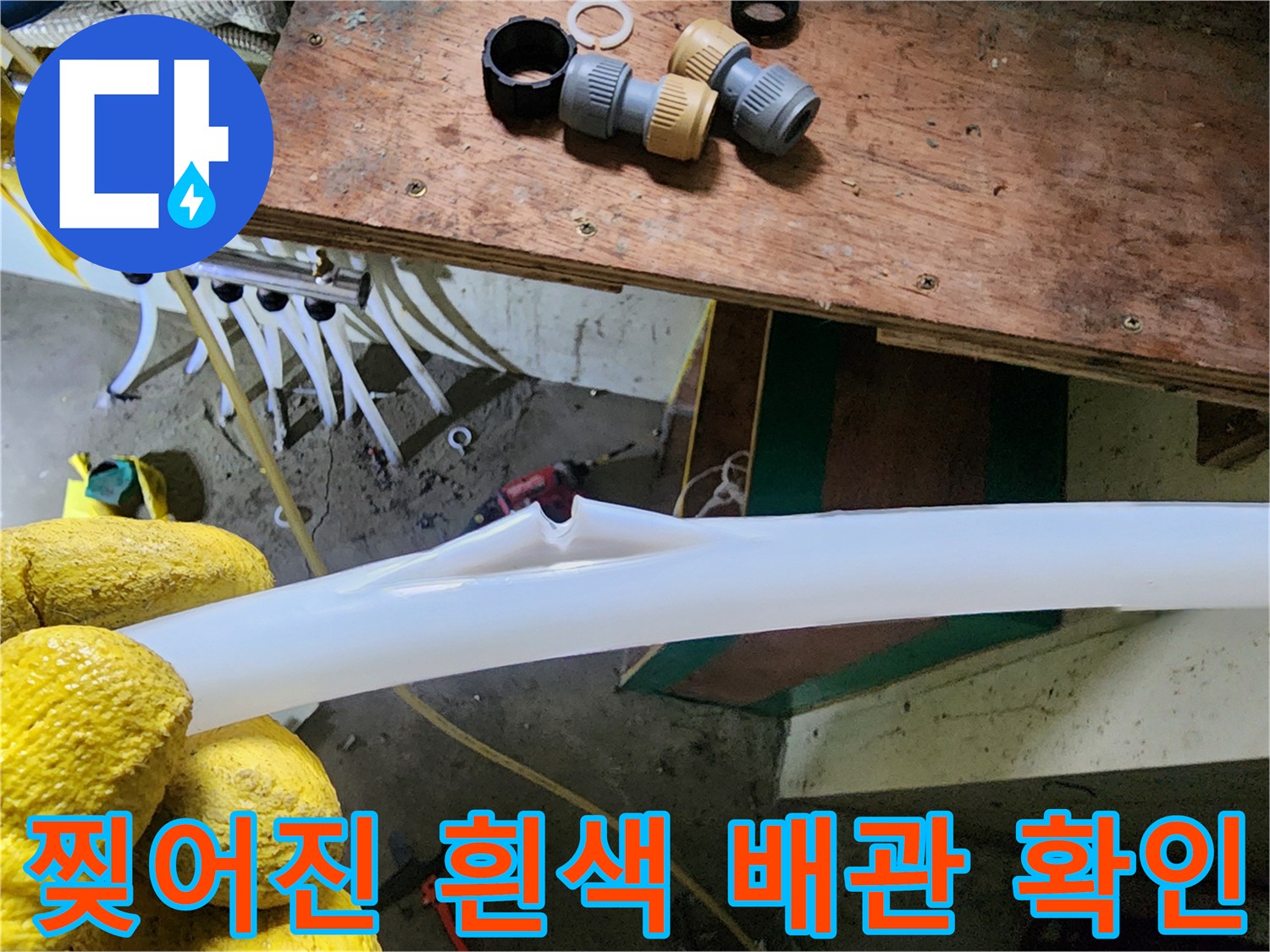 배관의 찢어진 틈새를 손으로 가리키며 누수 지점을 확인하는 모습