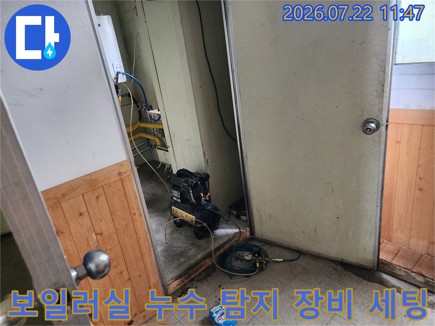 보일러실 내부 배관 옆에 배치된 검은색 누수 탐지 장비와 파란색 호스-연결 상태