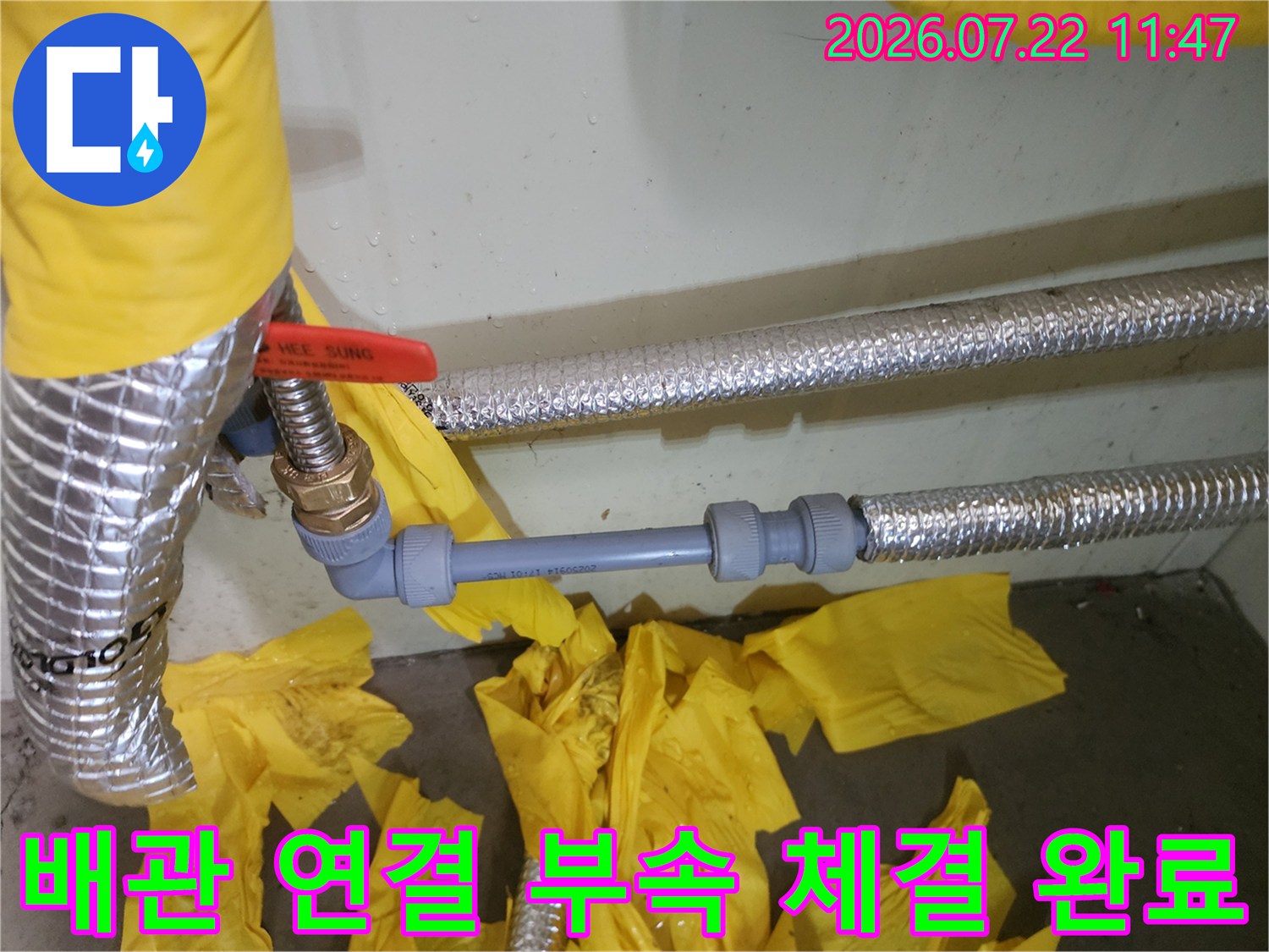 은색 보온재 사이로 드러난 새롭게 교체된 회색 배관과 금속 연결 부품