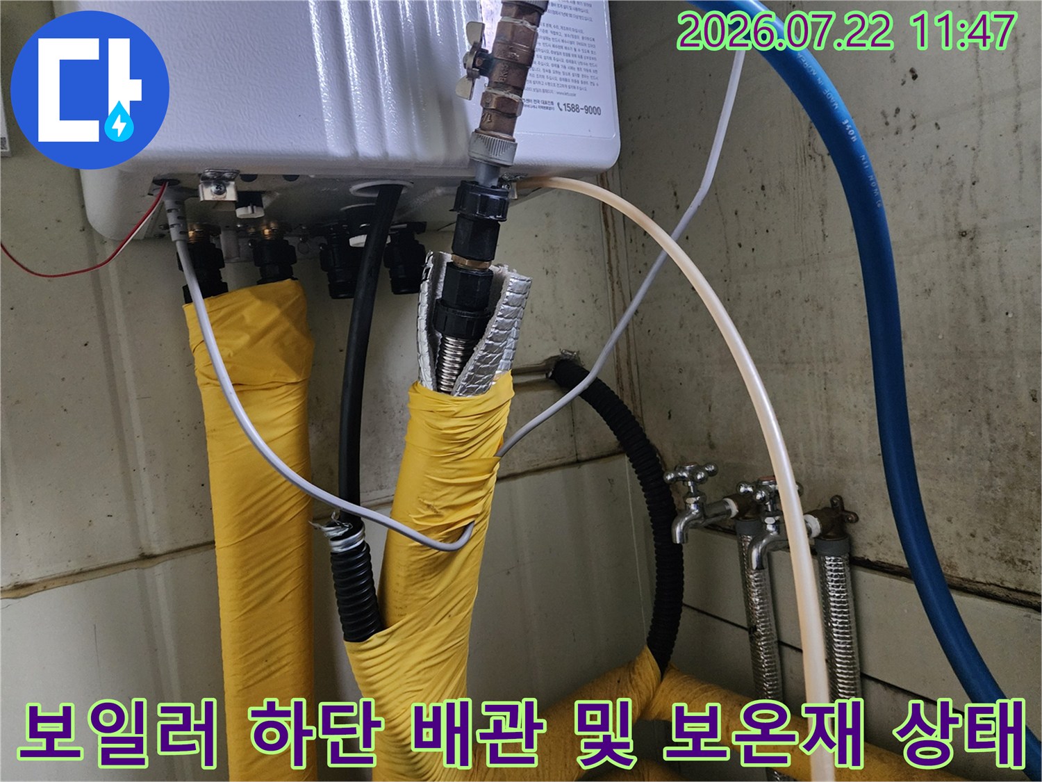 흰색 본체에서 뻗어 나온 노란색 보온재 배관들과 상단의 금속 제어 밸브 사진