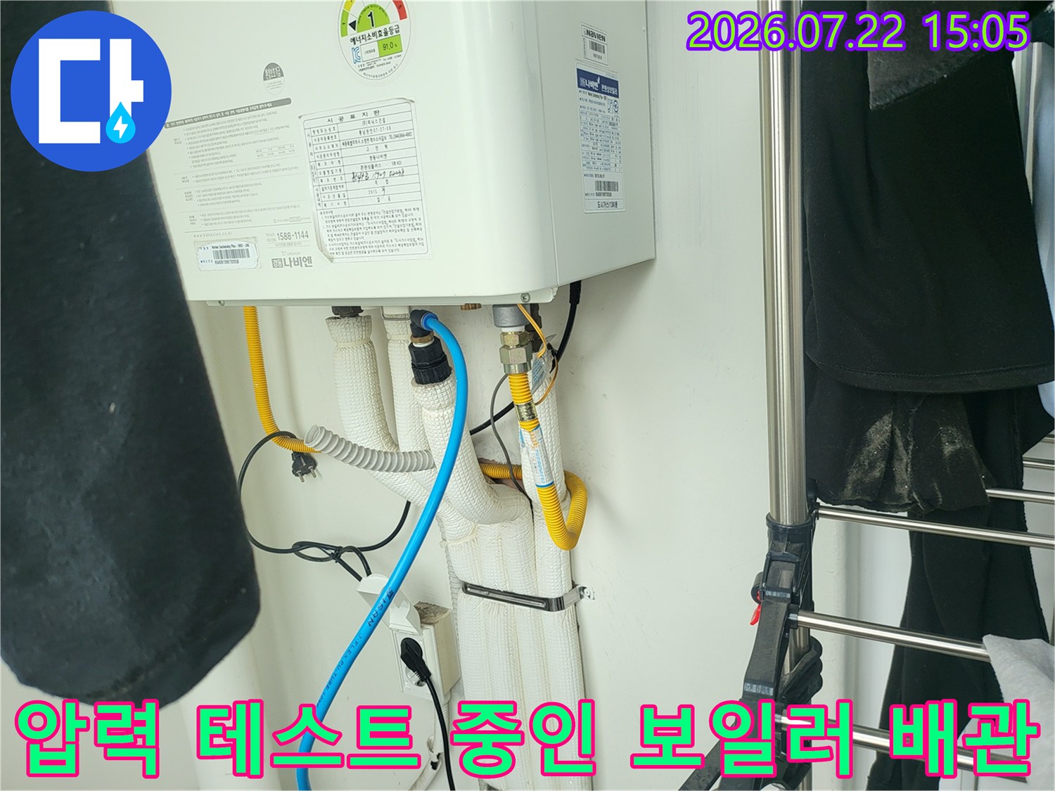 보일러 하부의 흰색 배관 뭉치와 연결된 파란색 진단용 호스의 모습