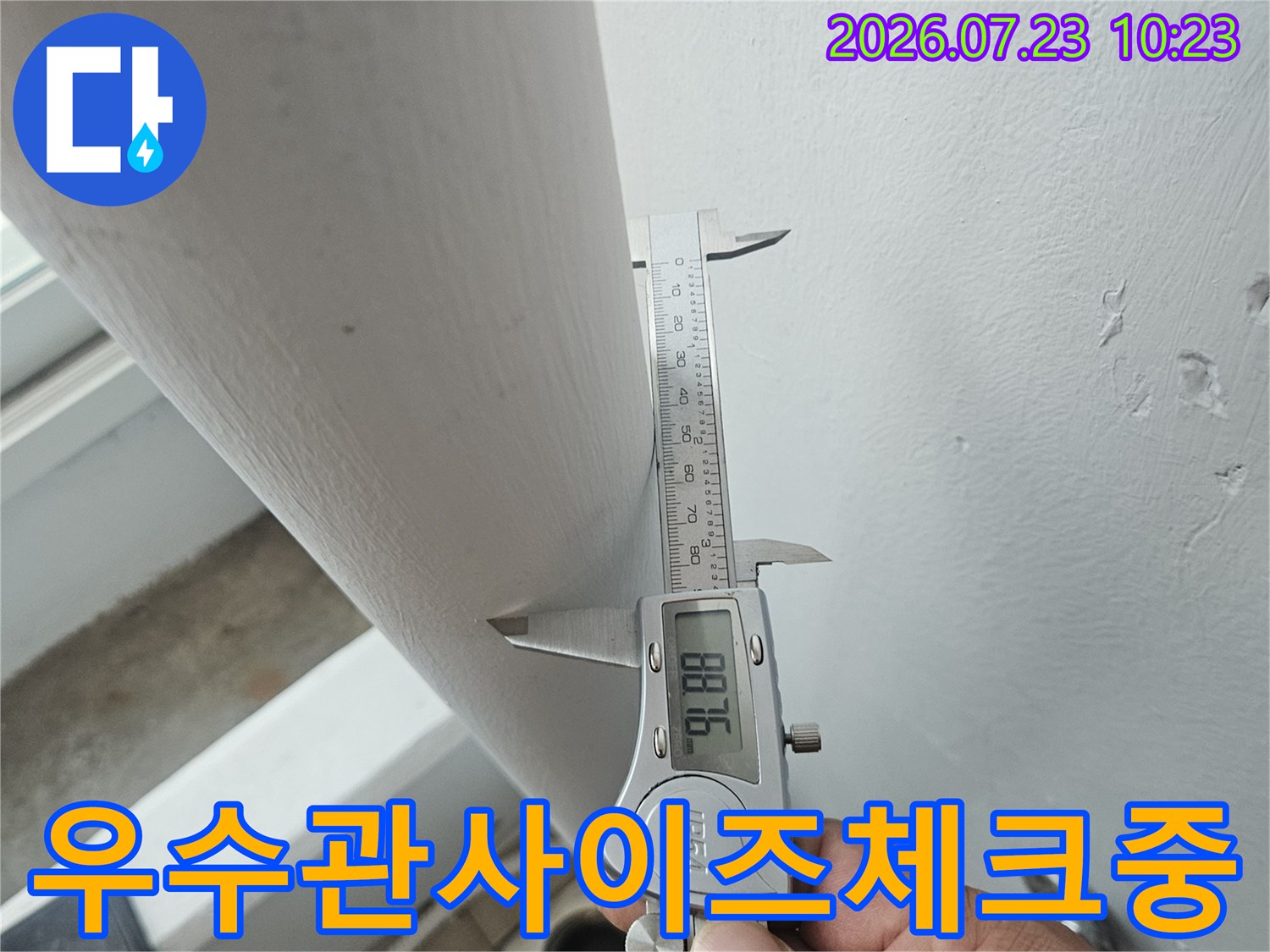 작업자가-흰색-배관에-금속제-측정기를-밀착시켜-치수를-재는-사진