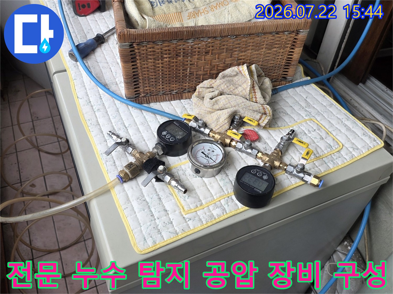 디지털 압력 게이지와 밸브 그리고 파란색 호스가 연결되어 세팅된 전문 누수 측정 도구들