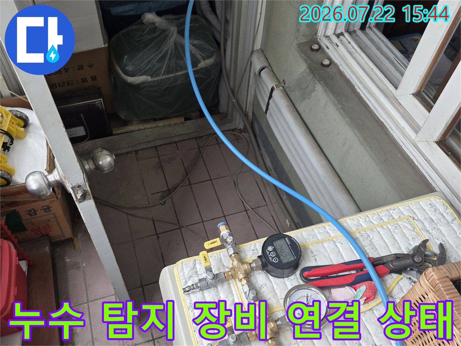 흰색 매트 위에 놓인 파란색 호스와 누수 점검용 압력 측정 장치들