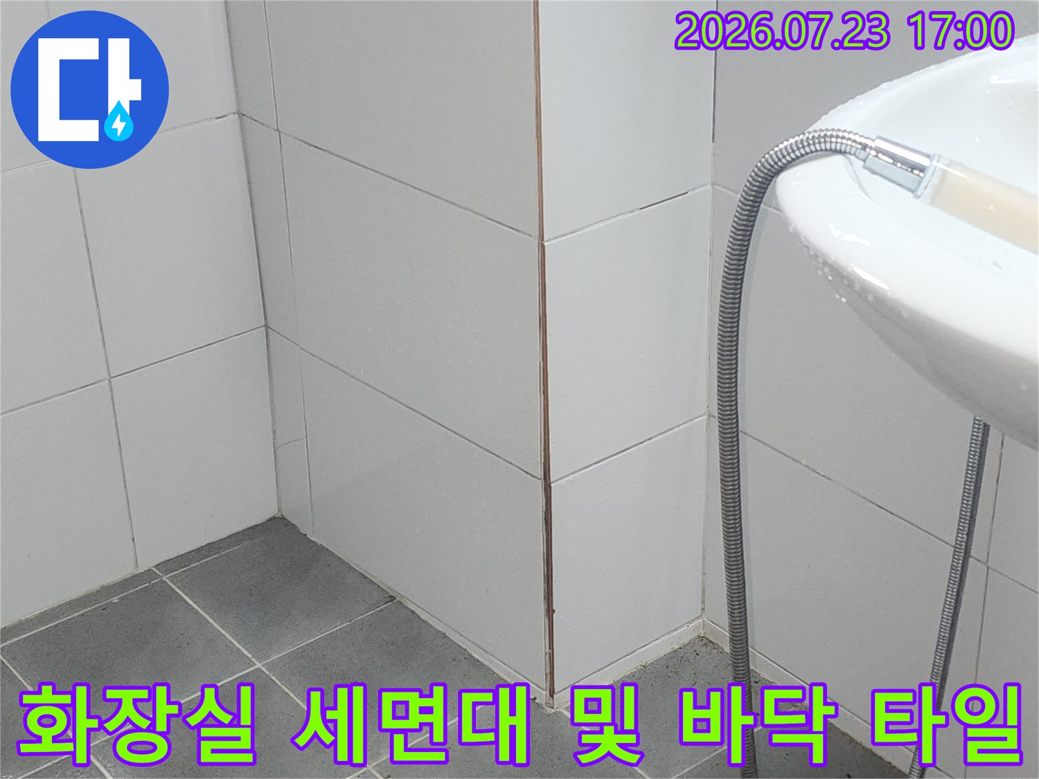 흰색 도기 세면대와 연결된 자바라 호스가 흰색 벽타일에 기대어 있는 사진