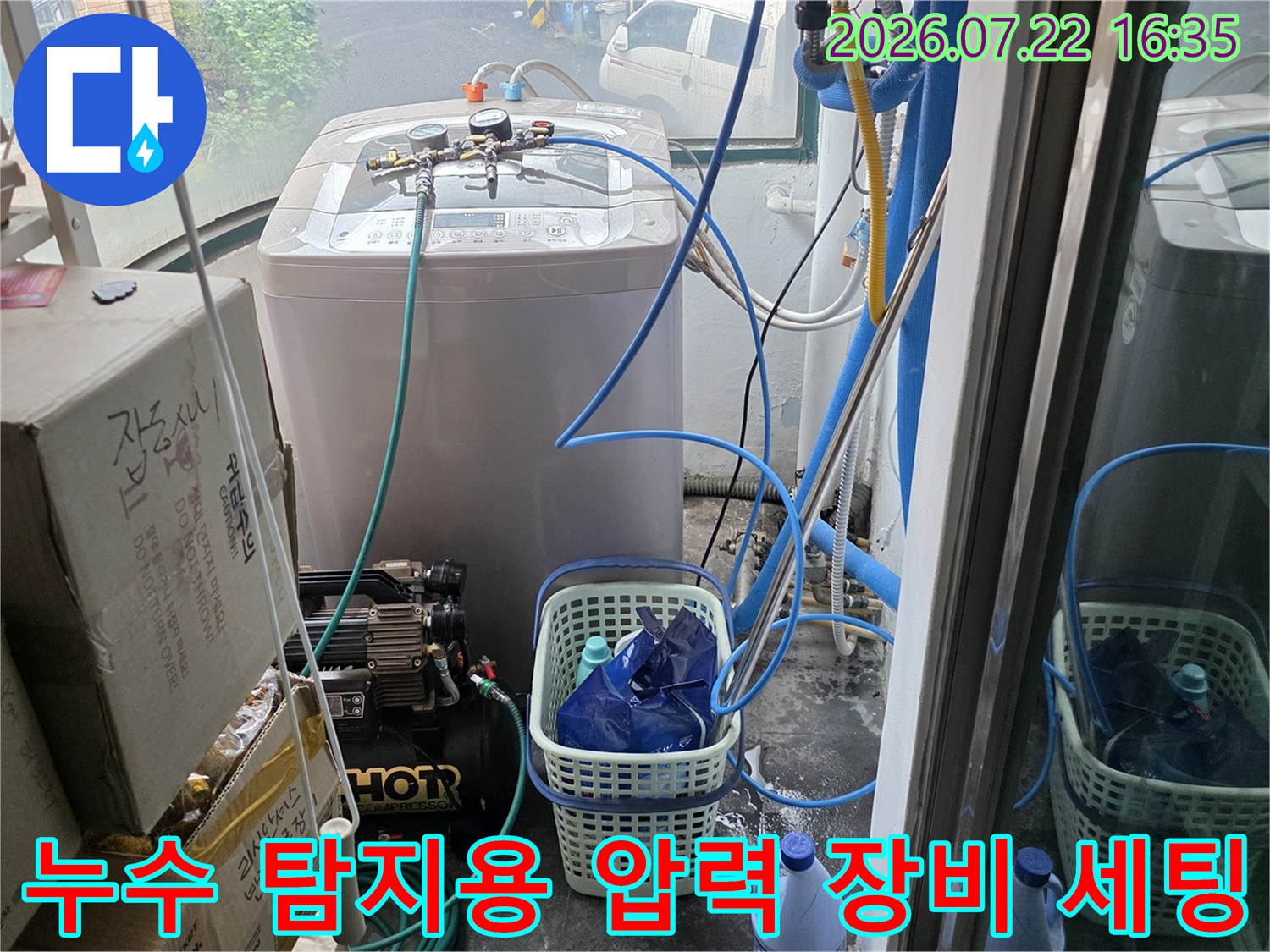 세탁실 내부-누수 지점을 찾기 위해 설치된 공압 테스트 장비와 파란색 연결 호스들