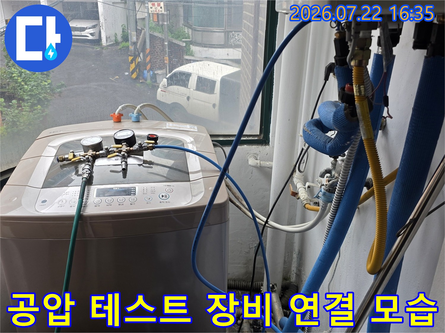 파란색 호스와 압력계가 세탁기 상단에 거치된 모습-배관 내부의 기밀성을 확인하는 과정