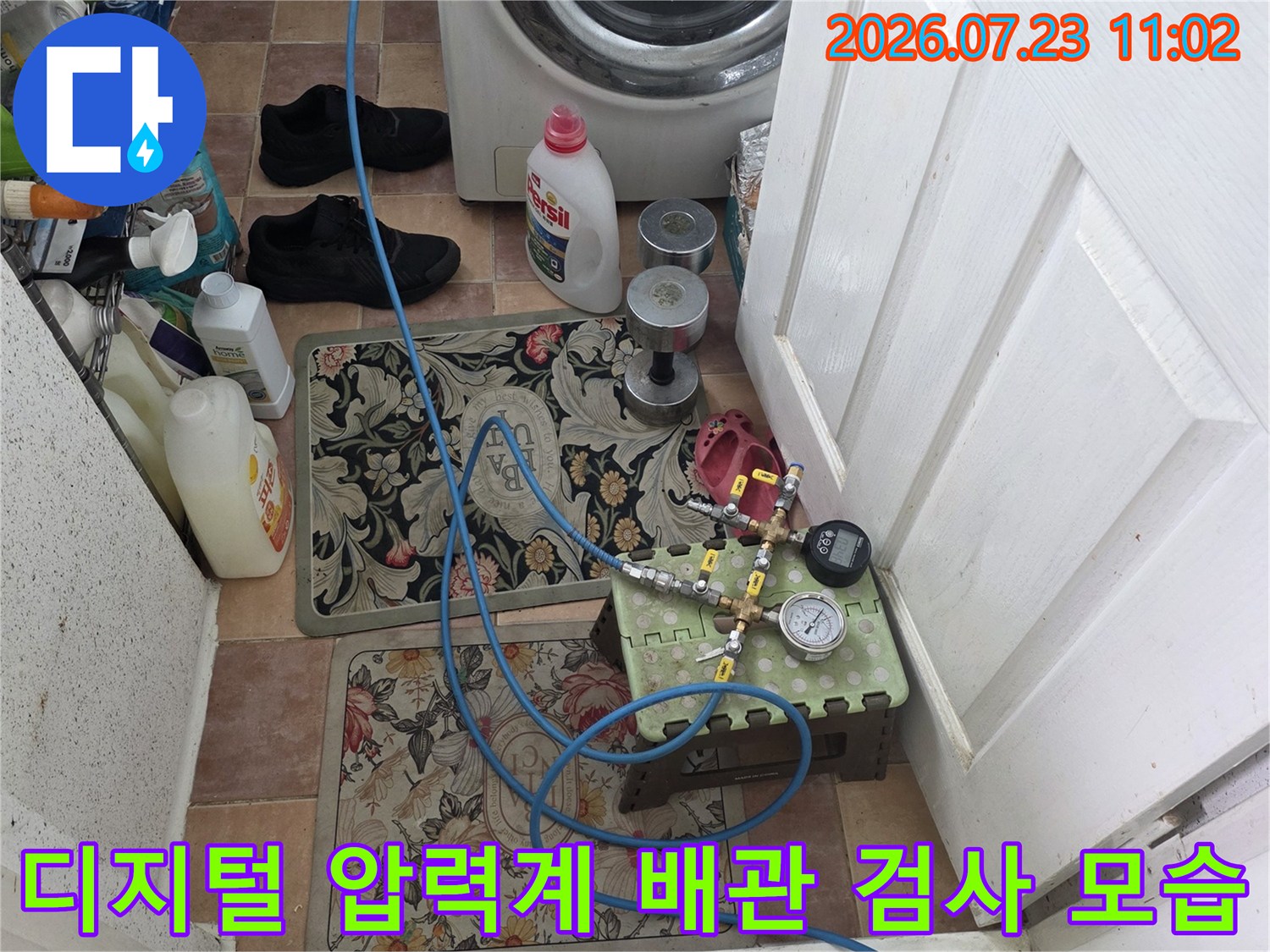 세탁실 바닥에 배치된 디지털 압력계-장비와 파란색 호스가 연결된 누수 진단 현장