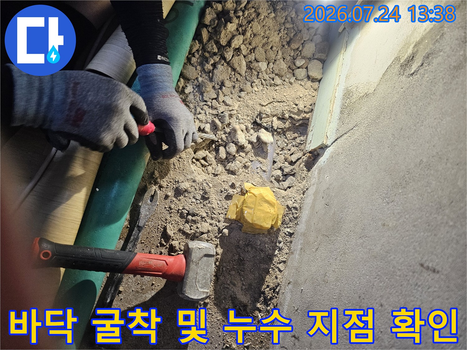 누수 지점을 찾기 위해 바닥을 굴착하고 망치와 장비를 배치한 현장 사진
