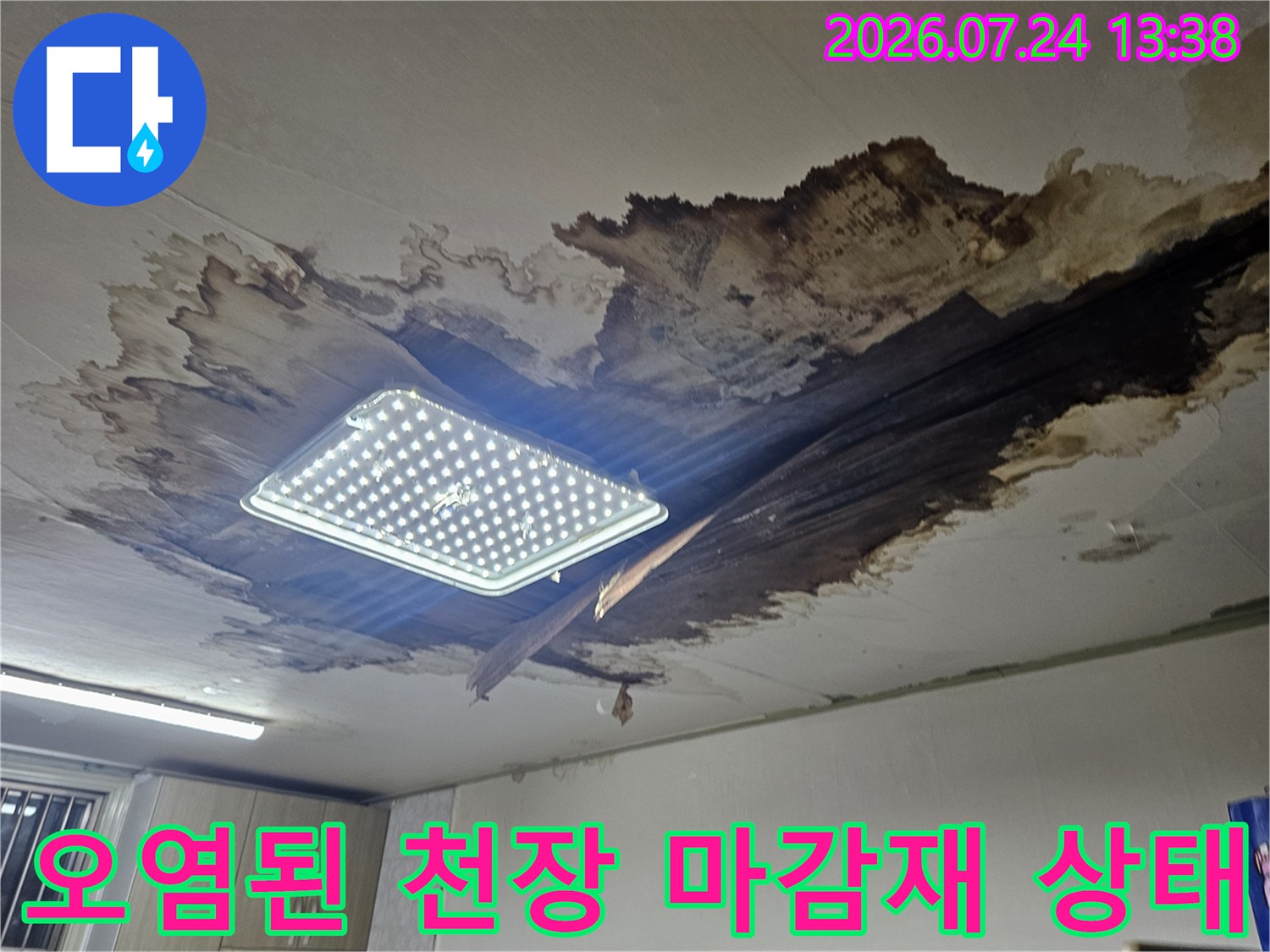 천장의 하얀 마감재가 뜯겨 나가고 내부의 어두운 부식 부위가 드러난 모습