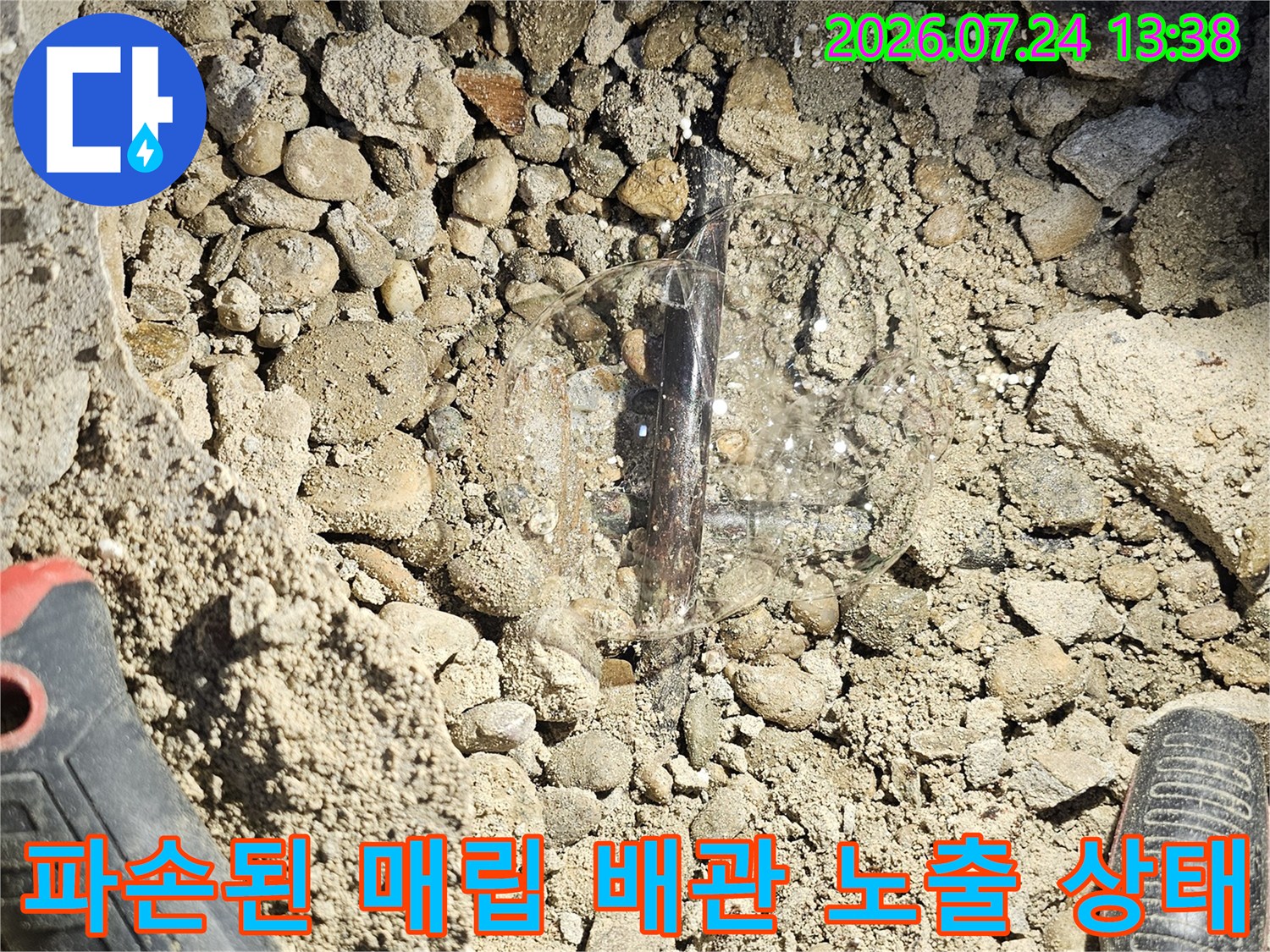 흙과 자갈 사이로-심하게 부식되어-검게 변한-수도 배관의 근접 사진