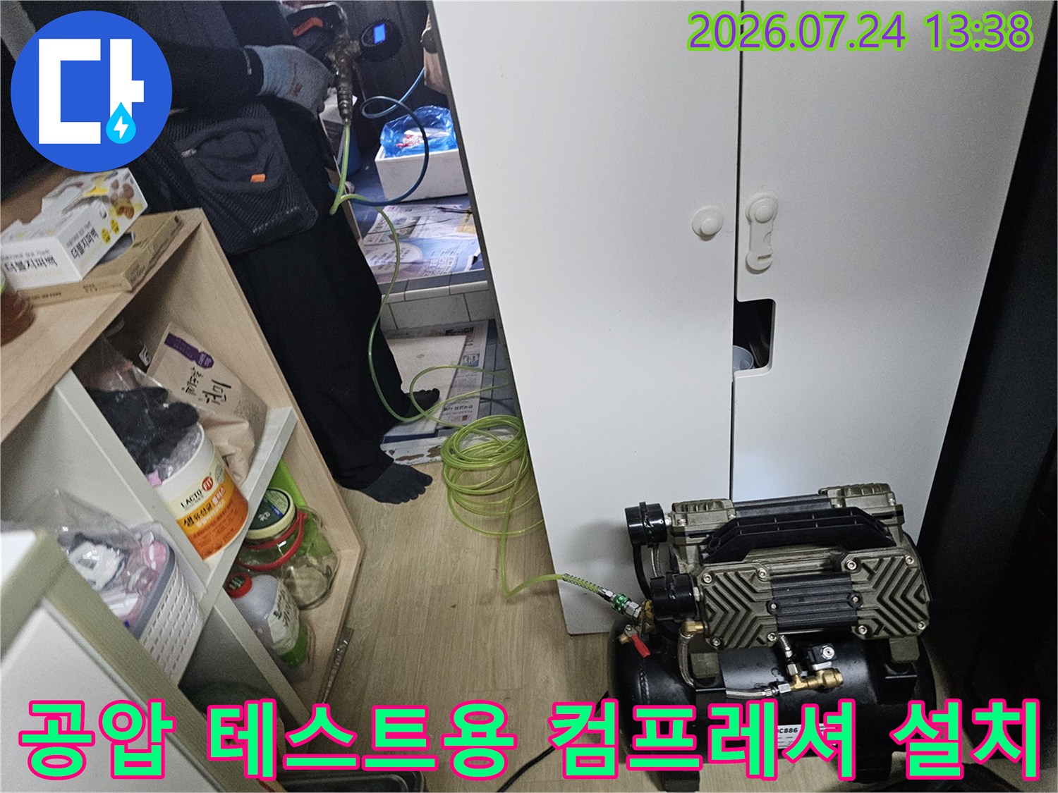 흰색 가구 옆 바닥에서 작동 중인 누수 탐지 장비와 연결 호스