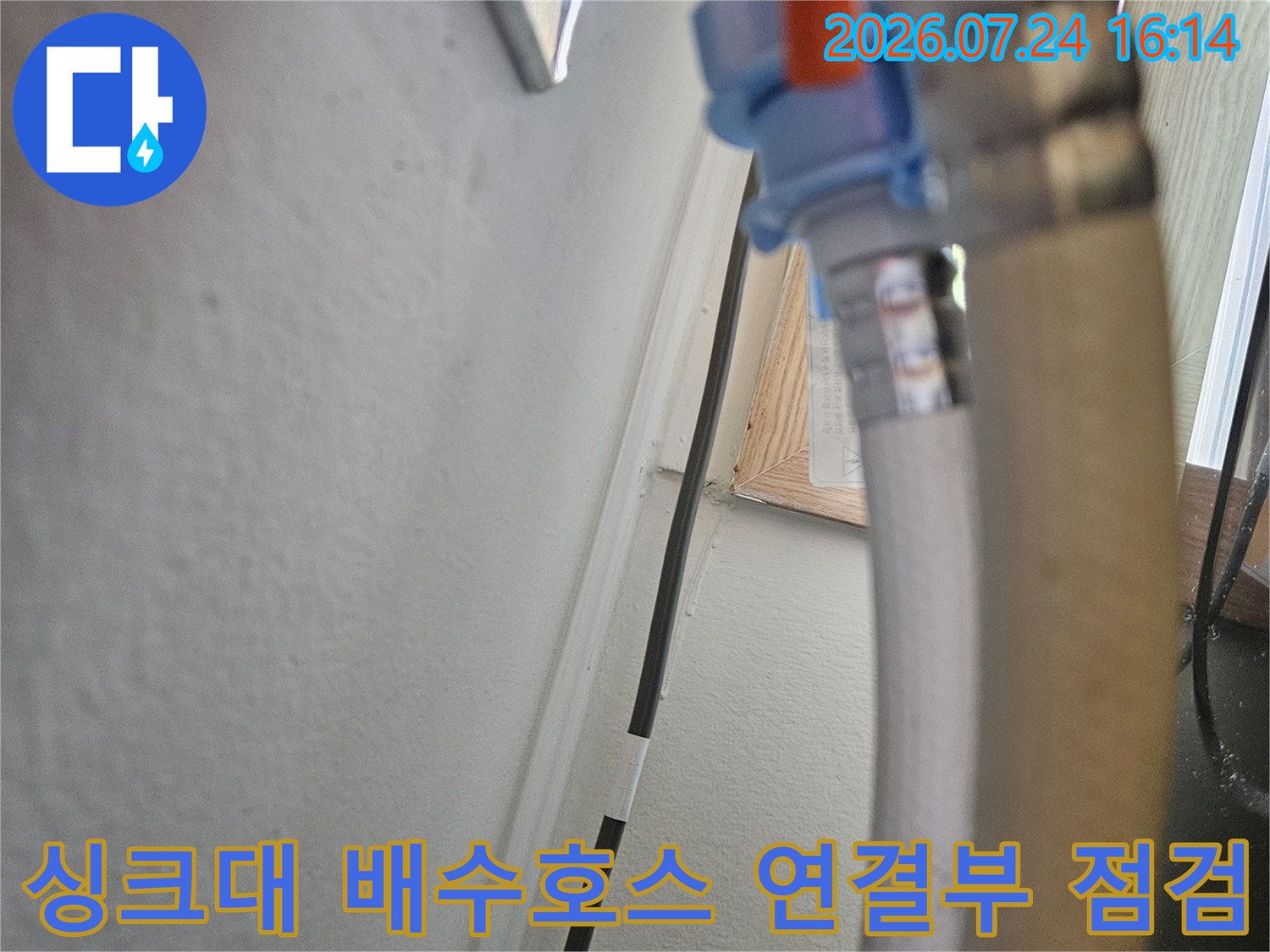 싱크대 하단에 위치한 노출된 배수 호스와 벽면 파이프 연결 부위의 근접 촬영