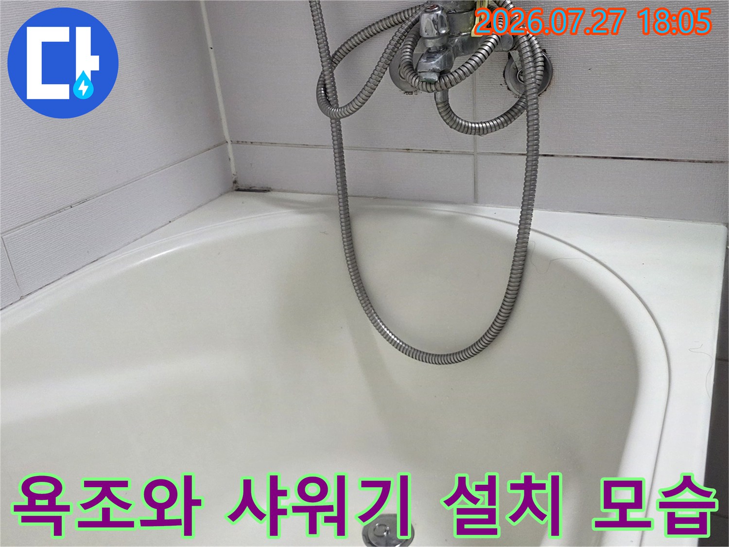 하얀색 욕조 위에 은색 샤워 호스가 걸려 있는 화장실 내부 사진