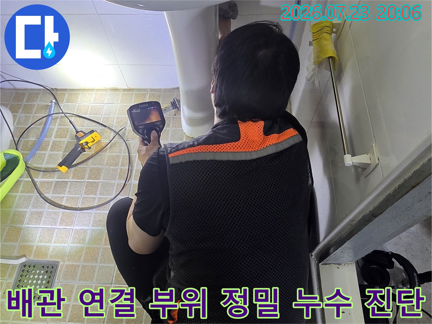 세면대 아래쪽 배관을 전문 장비로 세심하게 점검하며 누수를 추적하는 모습