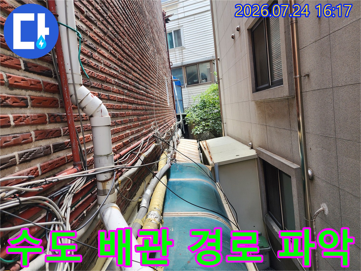 벽돌 벽면과 인접한 노출형 수도 및 가스 배관들의 복잡한 배치