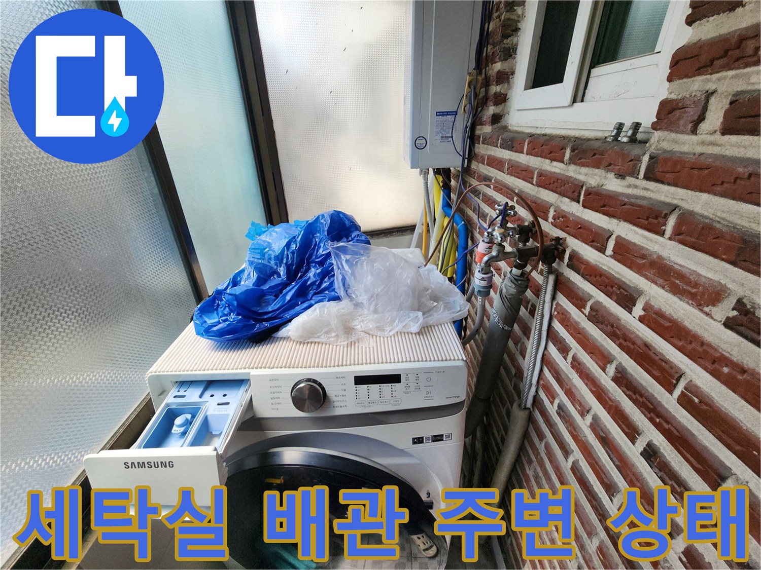 세탁기 옆 벽돌 외벽에 노출된 수도 배관과 계량기 모습