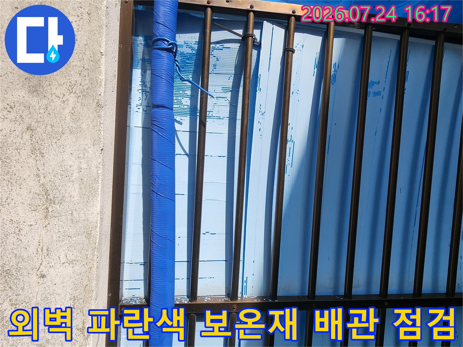 파란색 보온재로 마감된 외벽 노출 수도 배관을 점검하는 모습