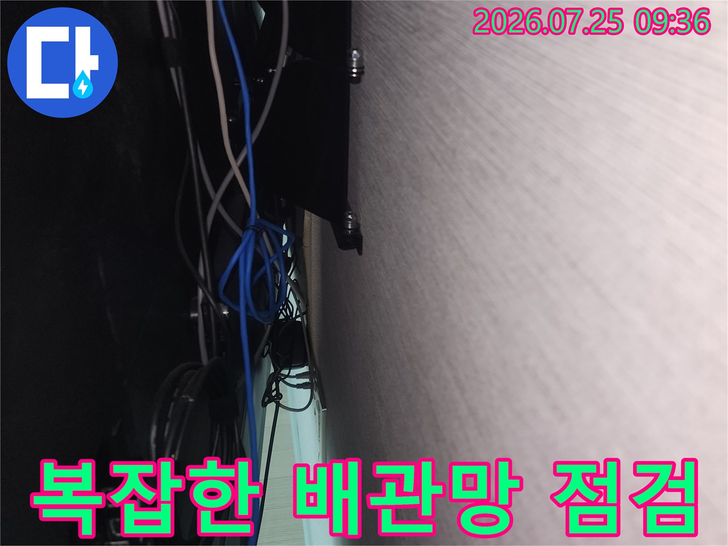 여러 가닥의 전선과 배관이 얽혀 있는 벽면 하단부 점검 모습