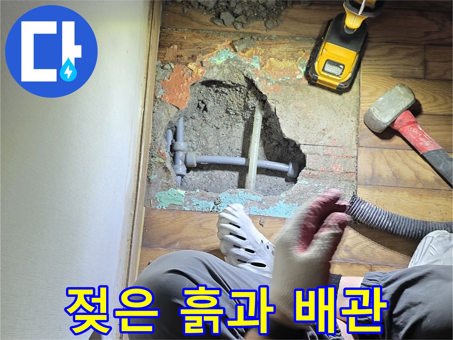 나무 마루를 파낸 자리에 드러난 젖은 흙과 배관 주변의 모습