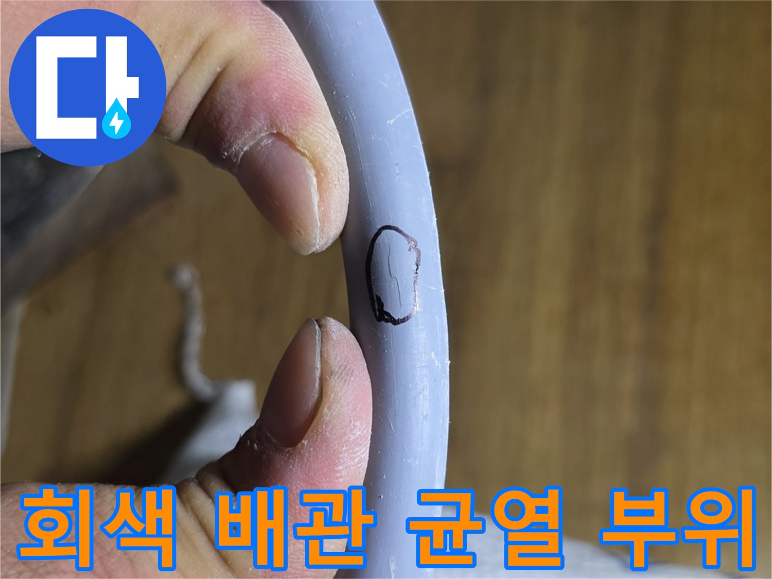 손으로 잡고 있는 회색 수도 배관의 파손 지점