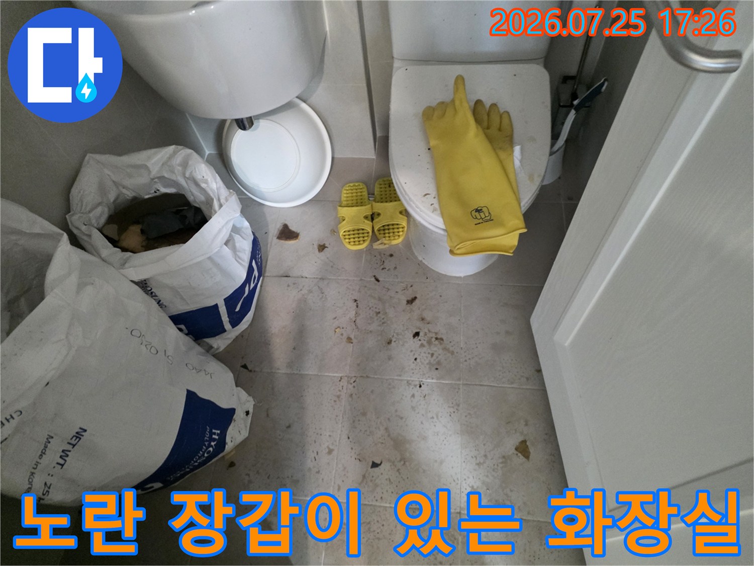 화장실 바닥에 배치된 작업용품과 배관 수선 자재들