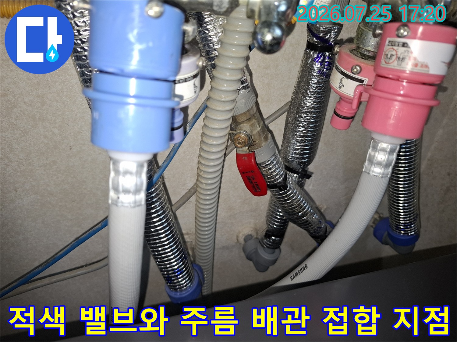 회색 주름관과 적색 핸들 밸브가 연결된 배관-누수 보수 작업 부위