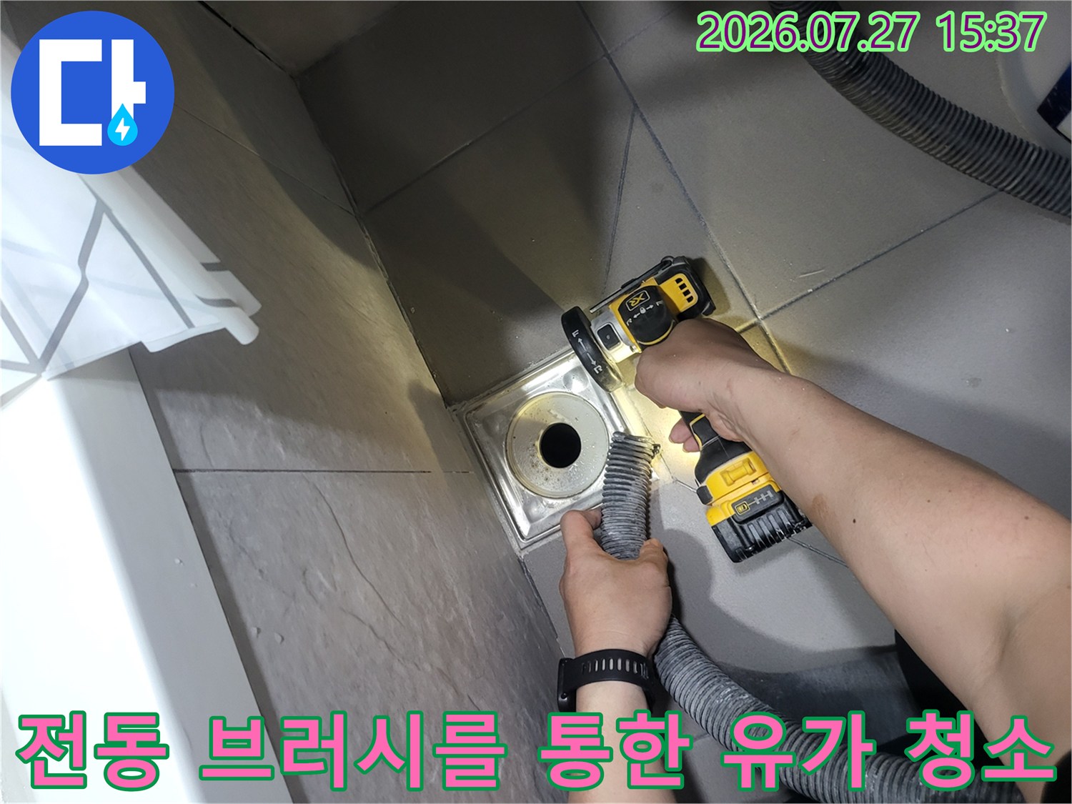 밝은 조명 아래에서 전동 장비로 배수구 주변의 이물질을 제거하는 작업 사진