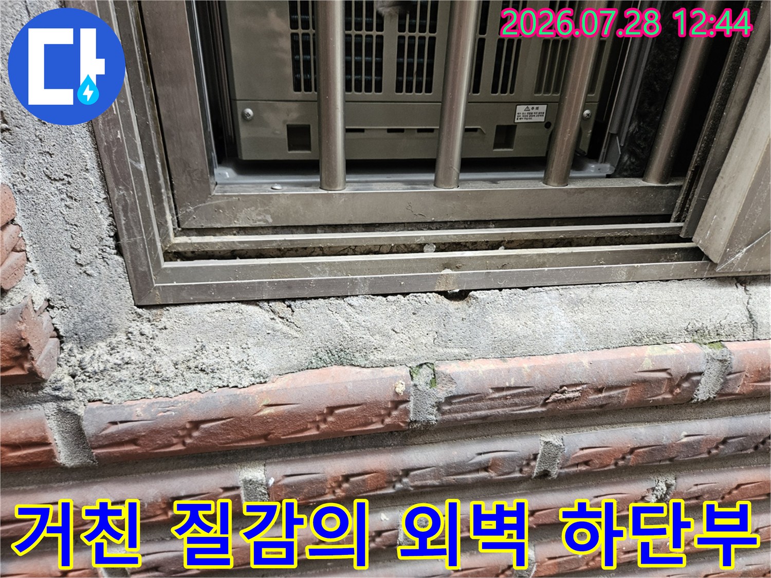 창문 틀 아래 노출된 거친 콘크리트면과 균열 상태