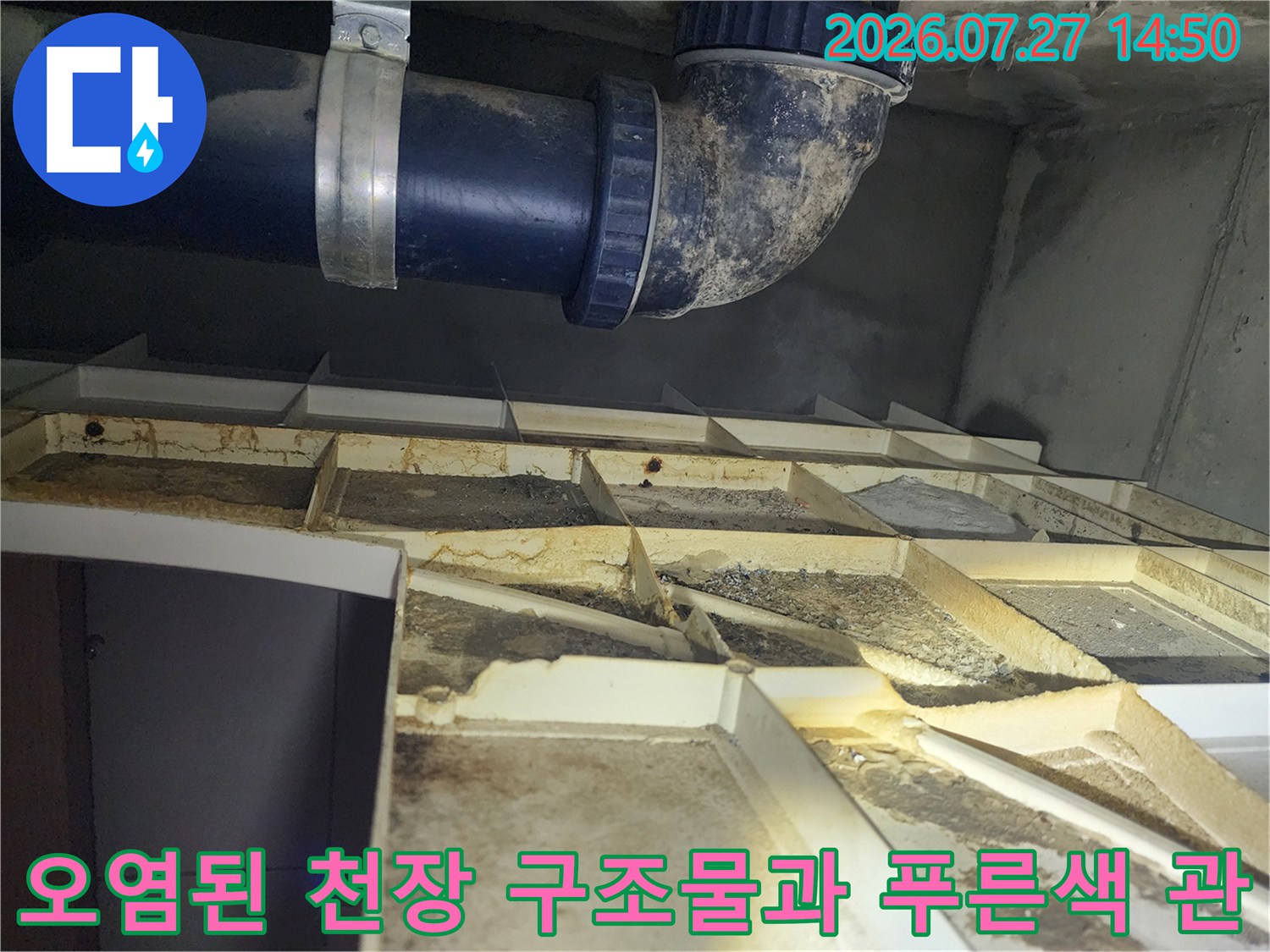 푸른색 하수 배관-그리고 그 위로 물 얼룩이 심하게 진 천장 내부 모습