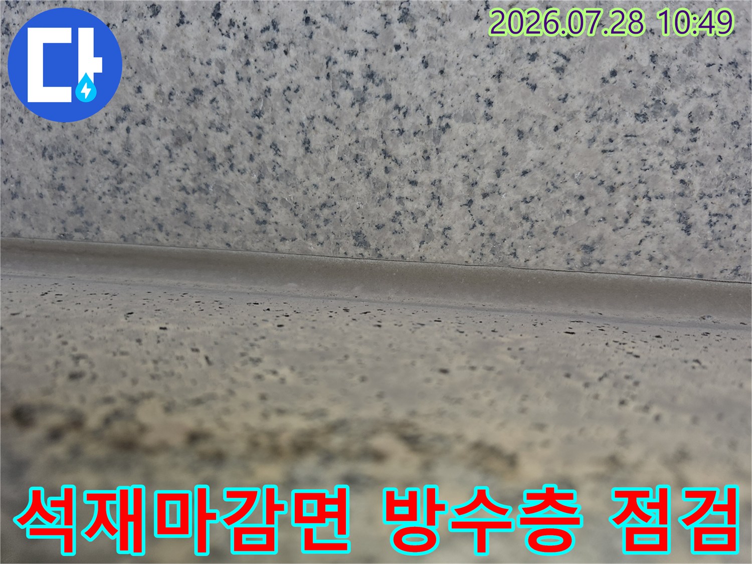 거친 질감의 석재 마감재와 바닥면이 만나는 지점의 방수 상태를 확인하는 모습