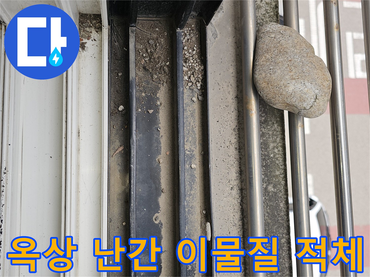 옥상 난간 하단부-배수 경로를 막고 있는 돌과 흙 먼지 상태