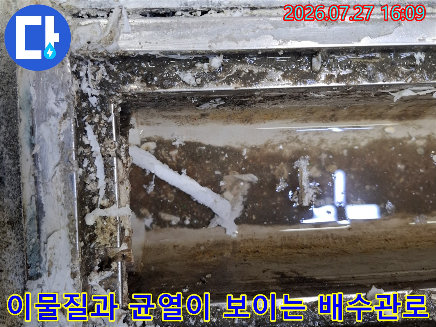 오염된 물기가 고여 있고 주변 마감재가 훼손된 주방 바닥 트랜치 내부 사진