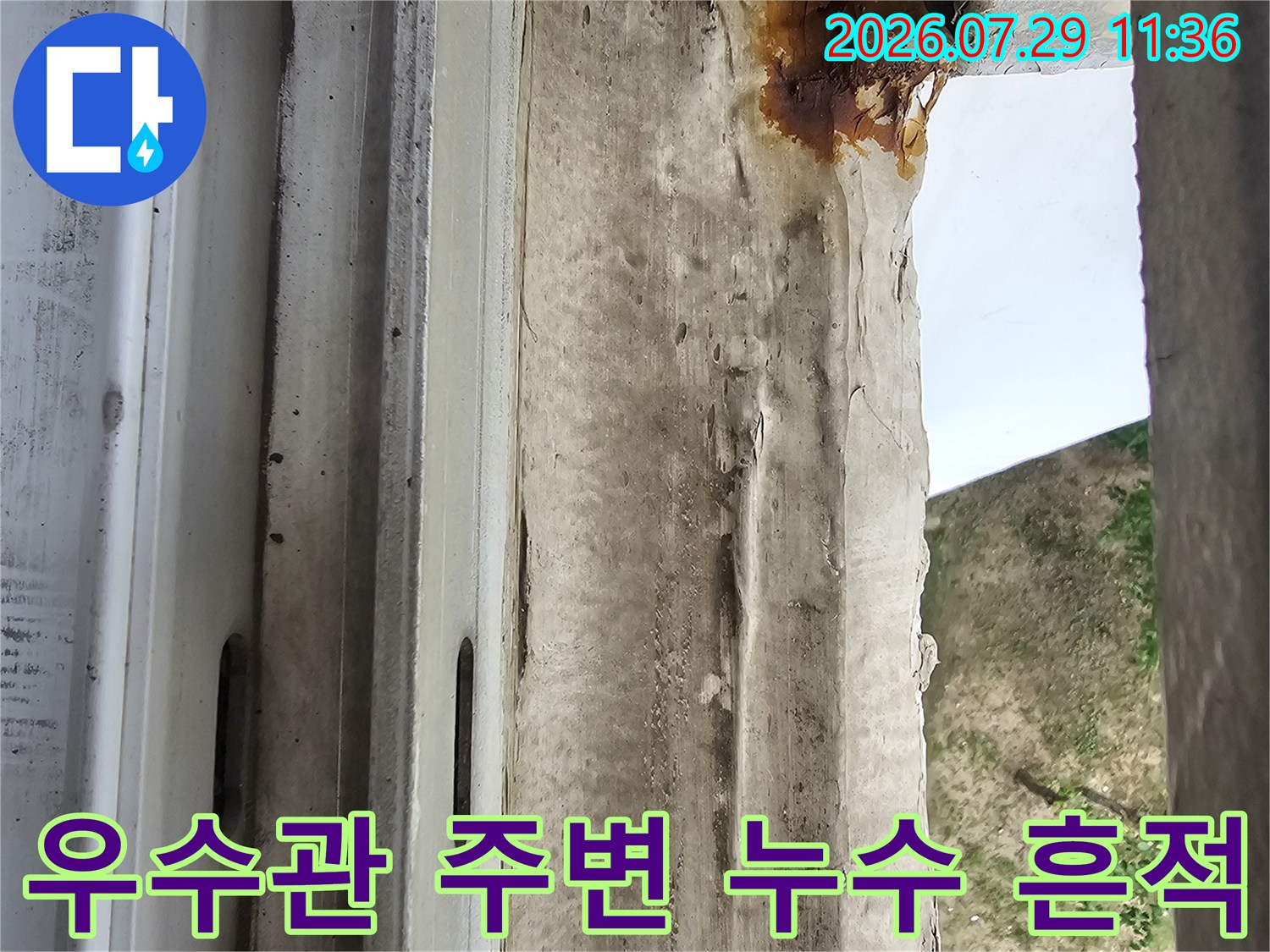 우수관 주변의 노후된 마감재와 누수로 인한 변색 부위
