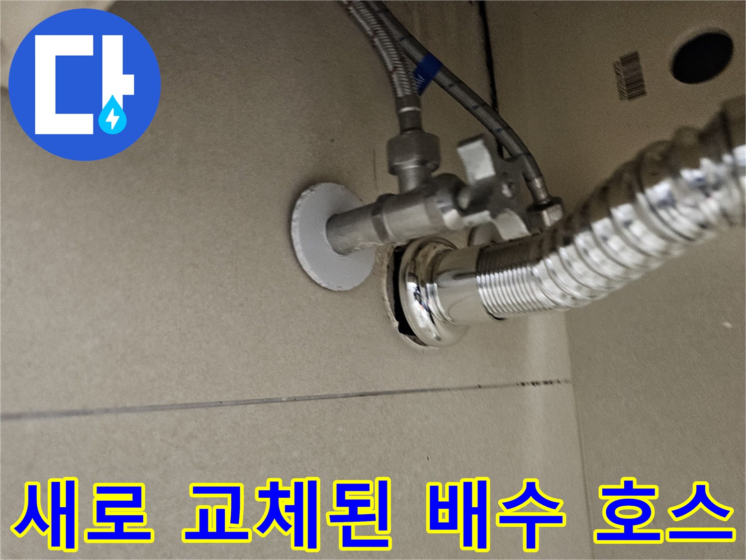 은색 주름관 형태의 세면대 배수 호스와 벽면 밸브 모습