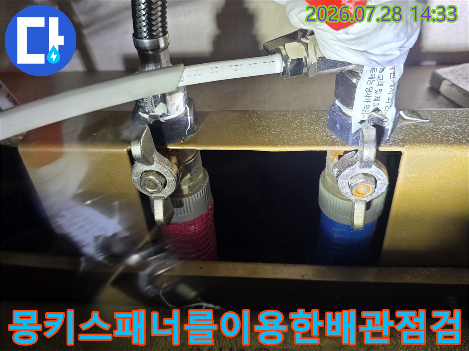 금속-제질의-분배기에-연결된-주름관을-공구로-풀어내어-누수-원인을-찾는-모습